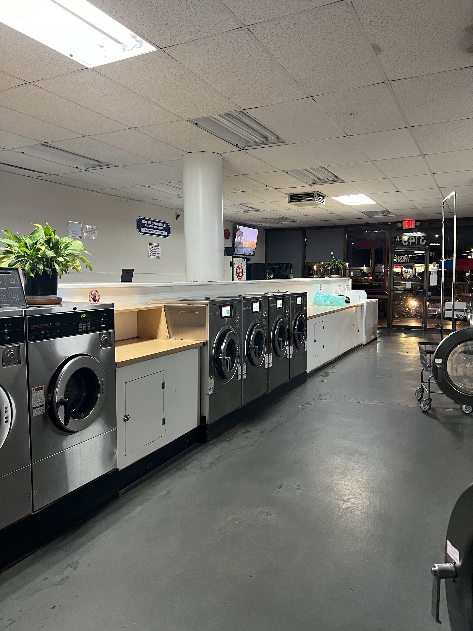 Row of stainless Speed Queen front-load washers with folding counters inside the laundromat